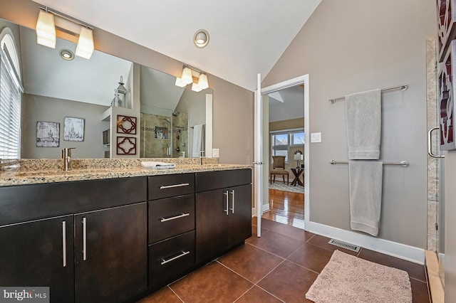 bathroom featuring tile patterned flooring, visible vents, a shower stall, lofted ceiling, and double vanity