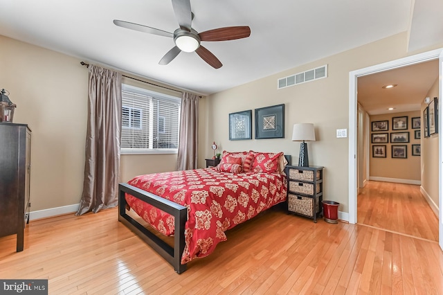 bedroom featuring ceiling fan, visible vents, baseboards, and light wood-style flooring