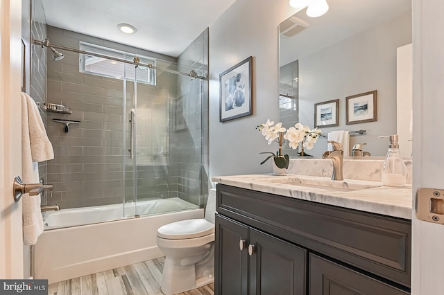 full bath with visible vents, toilet, wood finished floors, combined bath / shower with glass door, and vanity