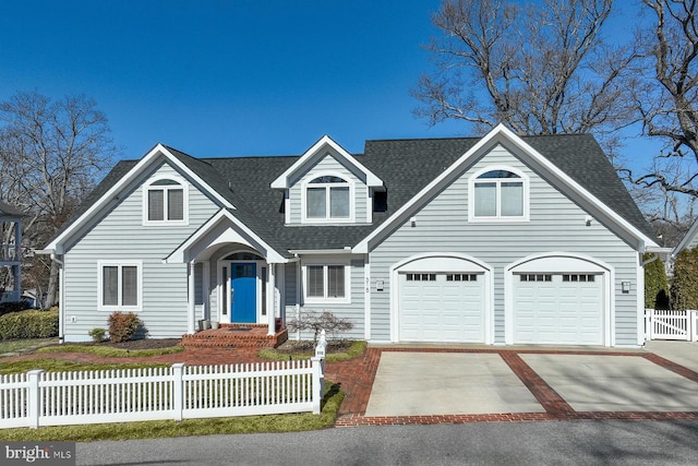 view of front of home with concrete driveway, a fenced front yard, and roof with shingles