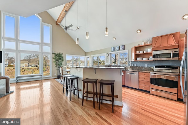 kitchen with a breakfast bar, decorative backsplash, light wood-type flooring, and appliances with stainless steel finishes