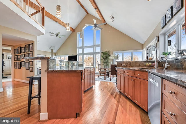 kitchen with light wood finished floors, ceiling fan, a breakfast bar, brown cabinetry, and stainless steel dishwasher