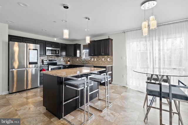 kitchen featuring a center island, light stone countertops, a breakfast bar, decorative backsplash, and appliances with stainless steel finishes