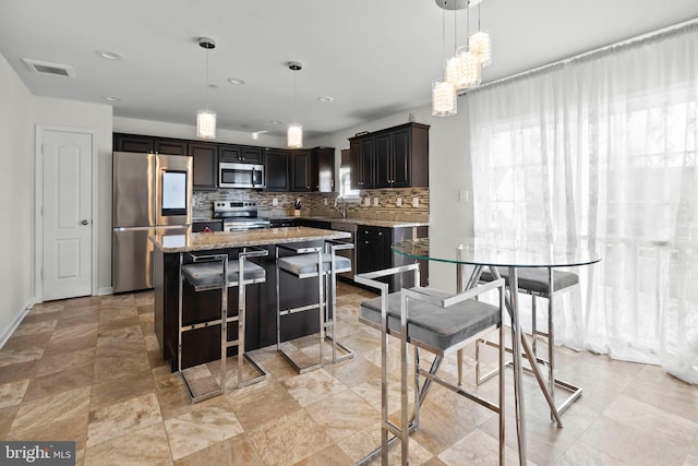 kitchen featuring tasteful backsplash, visible vents, a center island, light stone counters, and stainless steel appliances