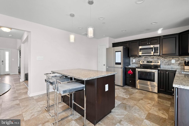 kitchen with tasteful backsplash, a center island, a breakfast bar area, appliances with stainless steel finishes, and hanging light fixtures