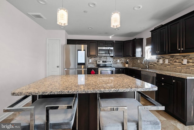 kitchen featuring visible vents, a sink, a kitchen breakfast bar, tasteful backsplash, and stainless steel appliances