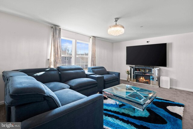 living area with a glass covered fireplace, baseboards, and carpet floors