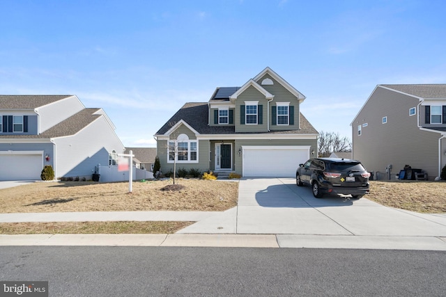 traditional-style house with a garage, roof mounted solar panels, and concrete driveway