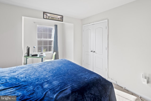 carpeted bedroom with a closet and baseboards