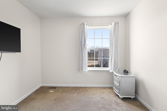 unfurnished room featuring baseboards and light carpet