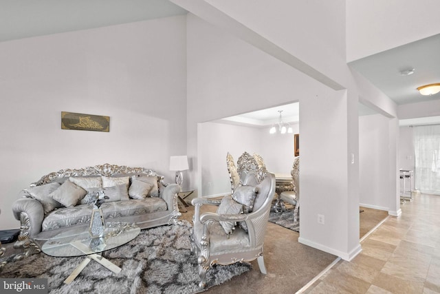 living area featuring an inviting chandelier, a high ceiling, and baseboards