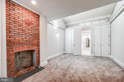 interior space featuring a brick fireplace, carpet, and baseboards