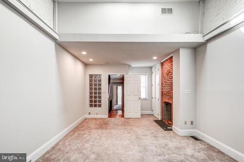 spare room featuring carpet floors, a fireplace, visible vents, and baseboards