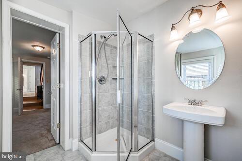 full bathroom with a stall shower and baseboards