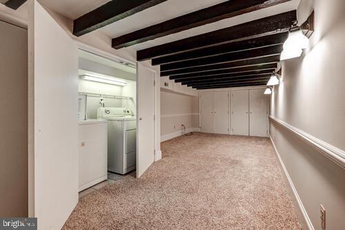 basement featuring light carpet, baseboards, and separate washer and dryer