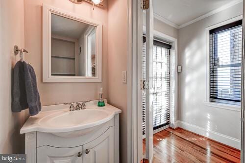 bathroom with plenty of natural light, baseboards, wood finished floors, and ornamental molding