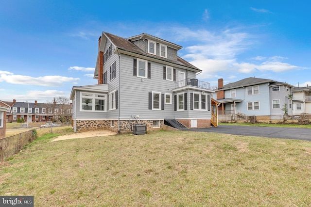 back of property with a lawn, a residential view, fence, and a balcony