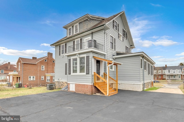 traditional style home with a balcony, a residential view, central AC, and entry steps