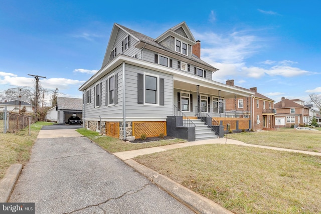 traditional style home with a chimney, a porch, a front yard, fence, and an outdoor structure