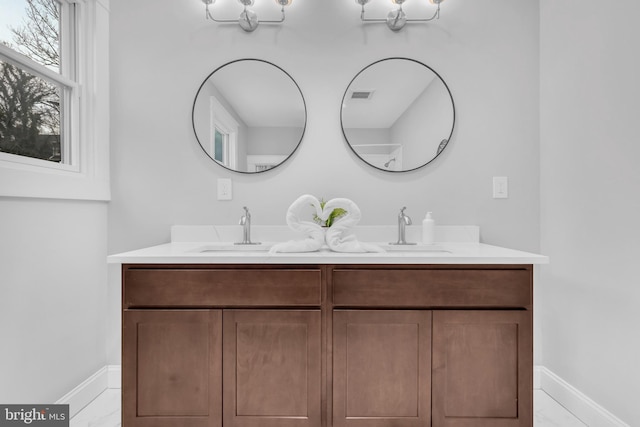 full bathroom with double vanity, baseboards, visible vents, and a sink