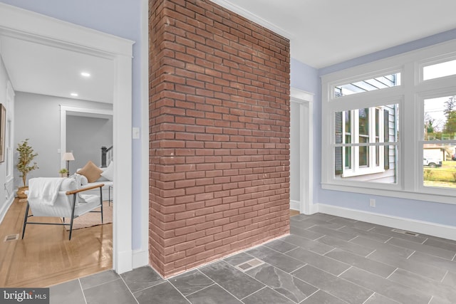 interior space with baseboards, brick wall, and an accent wall