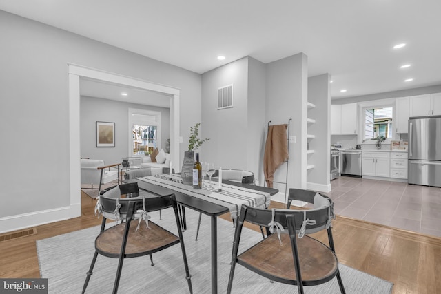 dining room with light wood-type flooring, visible vents, and plenty of natural light