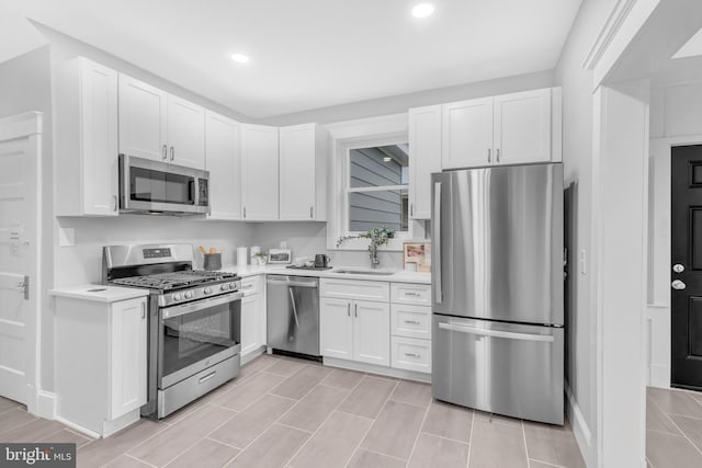 kitchen featuring stainless steel appliances, white cabinets, light countertops, and a sink