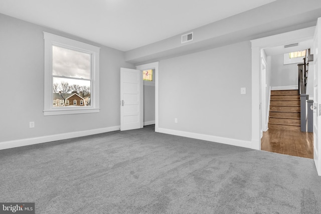 unfurnished bedroom with carpet floors, multiple windows, visible vents, and baseboards