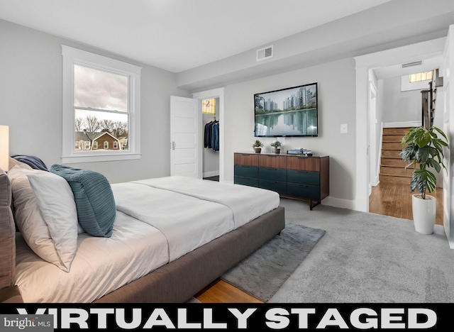 bedroom with a closet, a walk in closet, visible vents, and baseboards