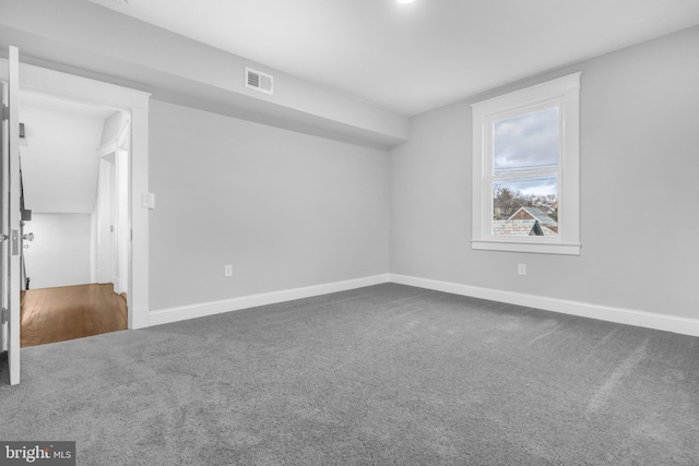 spare room with carpet floors, visible vents, and baseboards