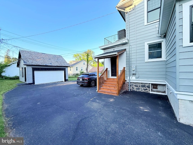 view of side of home with a balcony, an outdoor structure, and a garage