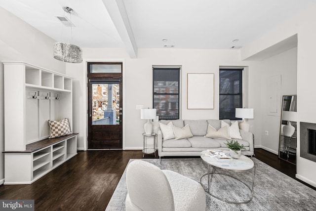 living area featuring beamed ceiling, a fireplace, wood finished floors, and baseboards