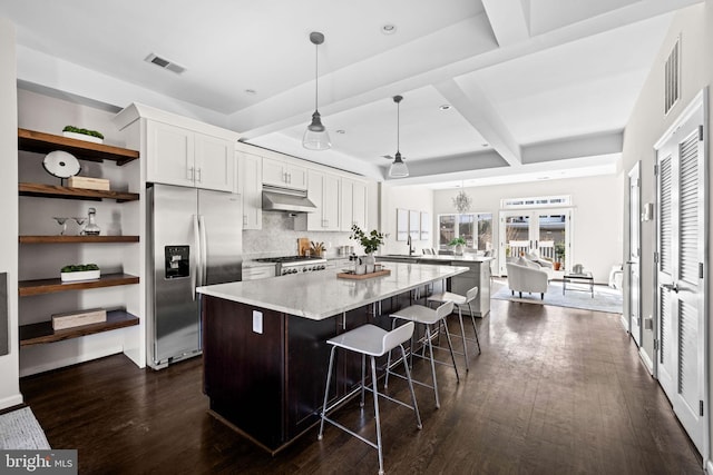 kitchen with range, stainless steel fridge with ice dispenser, a kitchen island, under cabinet range hood, and open shelves