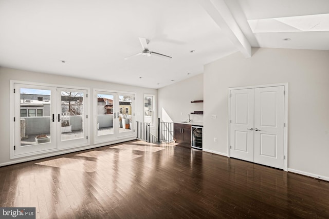 unfurnished living room featuring beverage cooler, lofted ceiling with beams, baseboards, and wood finished floors