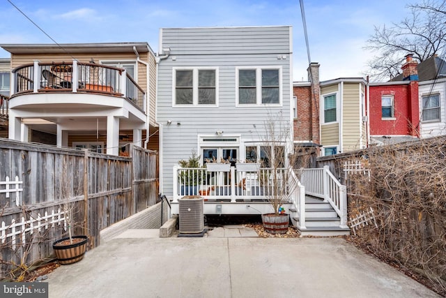 rear view of property with a patio area, fence private yard, a balcony, and central air condition unit