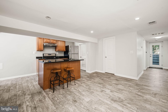 kitchen featuring stainless steel appliances, light wood-style flooring, visible vents, and under cabinet range hood