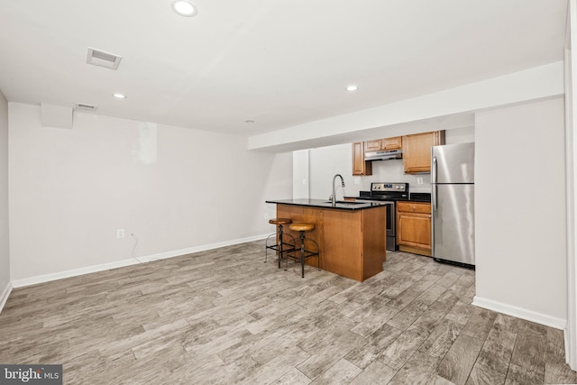 kitchen with under cabinet range hood, a sink, visible vents, appliances with stainless steel finishes, and dark countertops