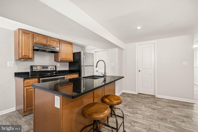 kitchen featuring stainless steel appliances, wood tiled floor, a sink, under cabinet range hood, and baseboards