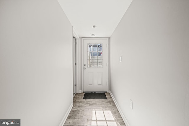 doorway with light wood finished floors and baseboards