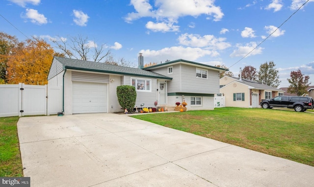 tri-level home with concrete driveway, entry steps, a gate, a garage, and a front lawn