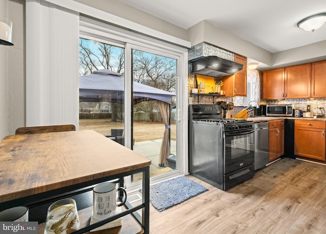 kitchen featuring stainless steel appliances, backsplash, brown cabinetry, light wood-style floors, and premium range hood