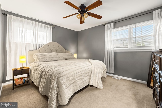 bedroom featuring light carpet, visible vents, baseboards, and ceiling fan