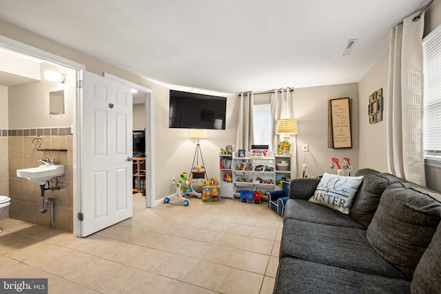 living area featuring visible vents, tile walls, and light tile patterned floors