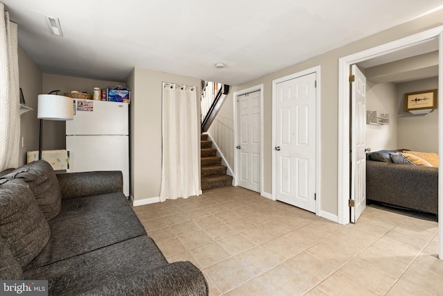 living area featuring light tile patterned floors, baseboards, visible vents, and stairway