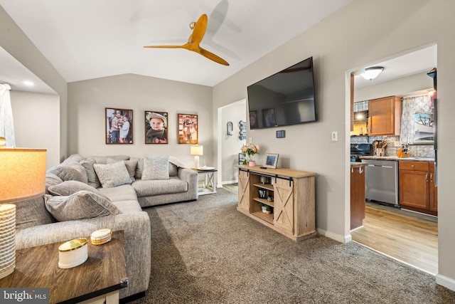 living room featuring ceiling fan, baseboards, vaulted ceiling, and light colored carpet