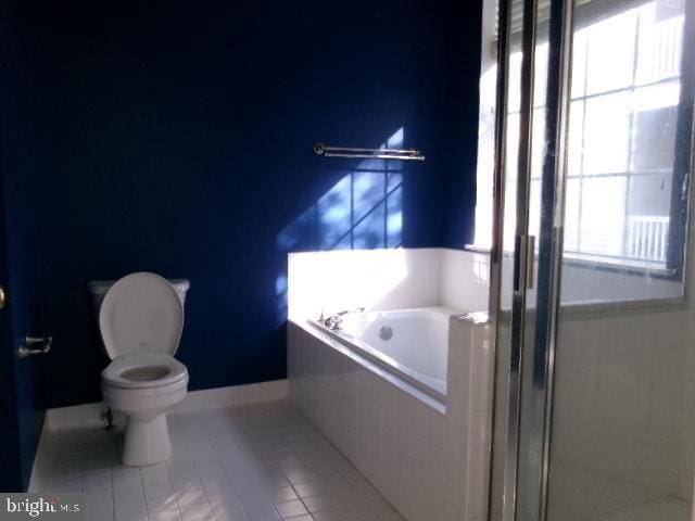 full bath featuring toilet, a garden tub, a shower stall, and tile patterned flooring