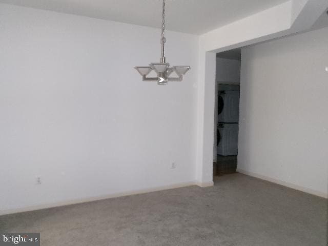 unfurnished dining area featuring carpet flooring, a notable chandelier, and baseboards