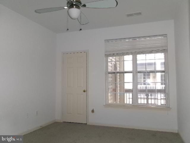 carpeted empty room featuring visible vents, ceiling fan, and baseboards