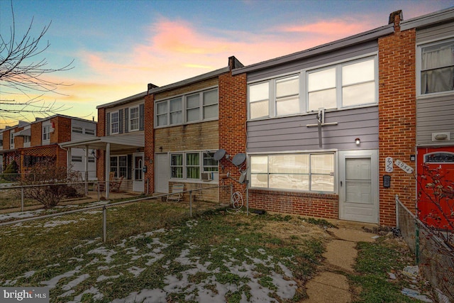 back of house at dusk with fence private yard and brick siding