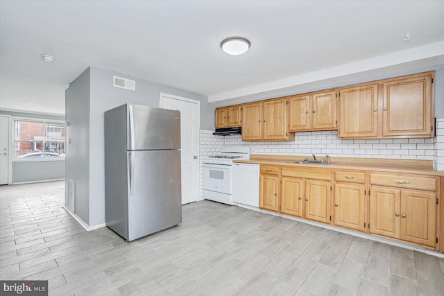 kitchen with white appliances, visible vents, decorative backsplash, under cabinet range hood, and a sink